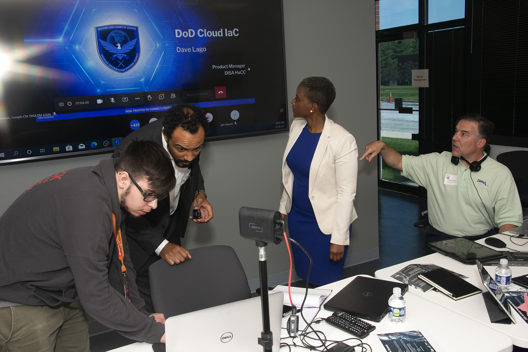 Image of Joseph Ramirez, DreamPort, and members of the DISAWERX team, Herman Mallory, Jeanelle Holder and Dr. Joseph Kovacic, setting up the next presentation at the DISAWERX Artificial Intelligence Summit at the DISAWERX lab in Columbia, Maryland. (DISA photo by Eric Glisson)
