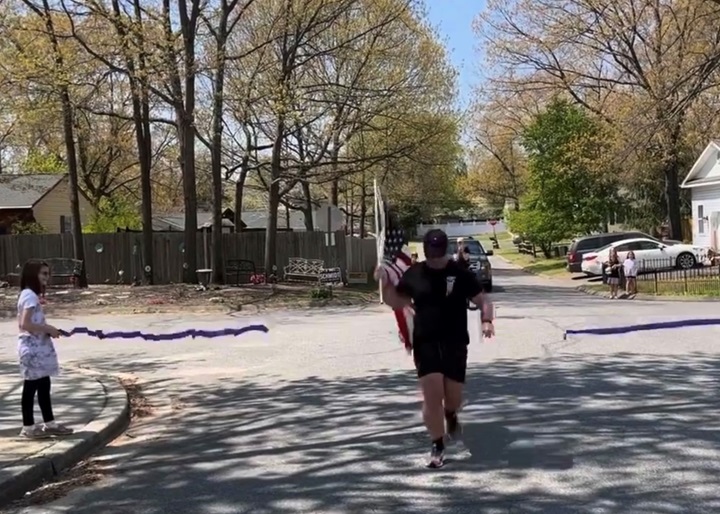 Kyle Butters crosses the finish line of his 22 Miles to Break Boundaries event April 24 carrying the U.S. flag that has been his constant companion since he joined the Army in 2009.