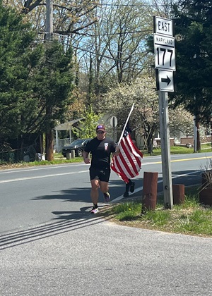 Kyle Butters carries a U.S. flag during his first four-mile lap of his 22 Miles to Break Boundaries event April 22. He also carried the flag on the pole during his last lap closing out 44 miles in 48 hours. On all the other laps, the flag was folded in his pack on his back. Butters acquired this flag at his first duty station in Fort Sill, Oklahoma, and it has been with him on all his active-duty missions around the world including Kuwait, Kyrgyzstan, and Kandahar, Afghanistan. 