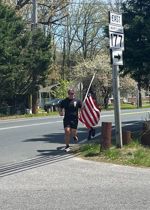 Kyle Butters carries a U.S. flag during his first four-mile lap of his 22 Miles to Break Boundaries event April 22. He also carried the flag on the pole during his last lap closing out 44 miles in 48 hours. On all the other laps, the flag was folded in his pack on his back. Butters acquired this flag at his first duty station in Fort Sill, Oklahoma, and it has been with him on all his active-duty missions around the world including Kuwait, Kyrgyzstan, and Kandahar, Afghanistan.