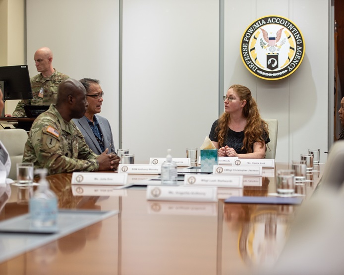 Sharon Woods, DISA J-6 Command, Control, Communications, and Computers Enterprise Directorate director speaks with John Figuerres, DPAA Operations acting deputy director, and U.S. Army Command Sgt. Maj. Anthony Worsley who sit to her right at a conference table.