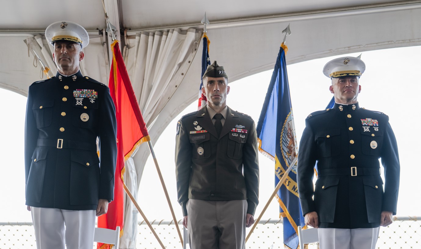 From left to right: Marine Corps Col. Michael T. Hlad, Army Lt. Gen. Paul T. Stanton, and Marine Corps Col. Jared C. Voneida stand at attention in front of military flags during the DISA Pacific change of command ceremony.